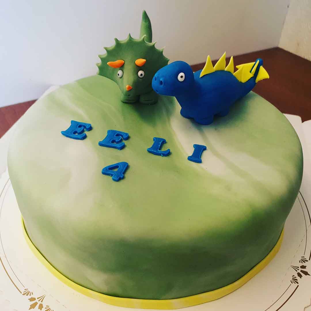 Vihreä kakku, jonka päällä on kaksi erilaista dinosaurushahmoa