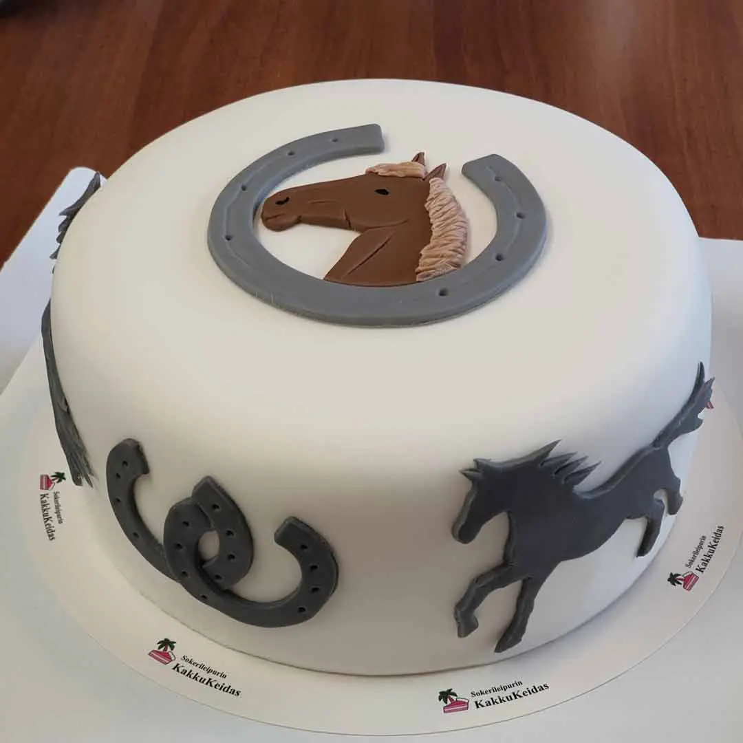 Hevoskuvioin ja hevosenkengin koristeltu valkoinen kakku