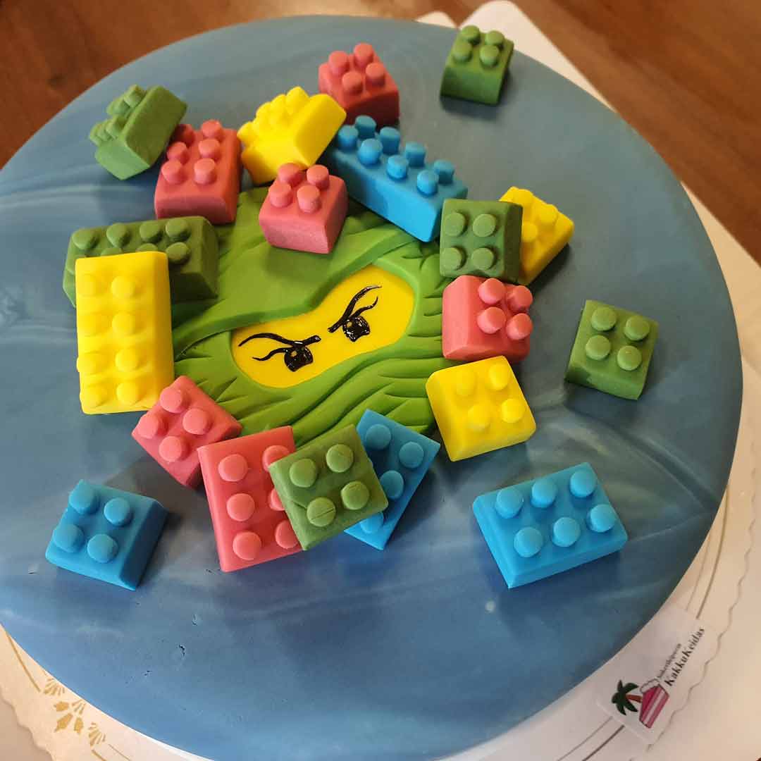 Sininen kakku, jonka päällä on Lego-ninjahahmo ja syötäviä legopalikoita