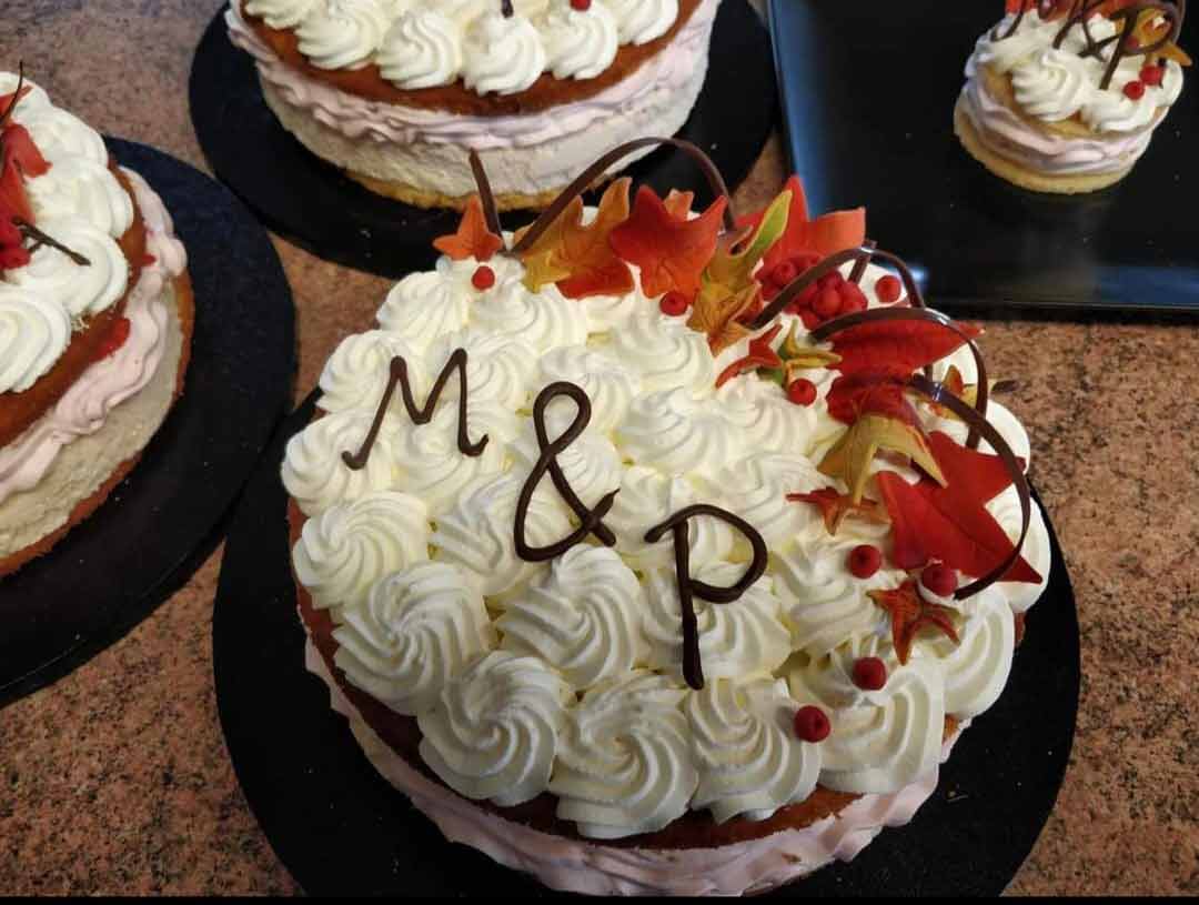 Kermalla koristeltu kakku, jonka päällä on ruskalehden näköisiä koristeita ja suklaaspiraaleja